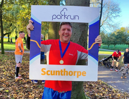 Man holding up a sign to show he has run the Park Run in Scunthorpe