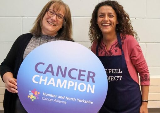 Two women who are cancer alliance tutors holding a sign to advertise the cancer alliance